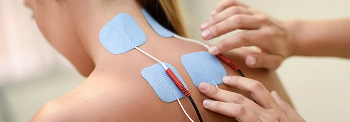 Chiropractor placing electrical stimulation pads on patient's back.