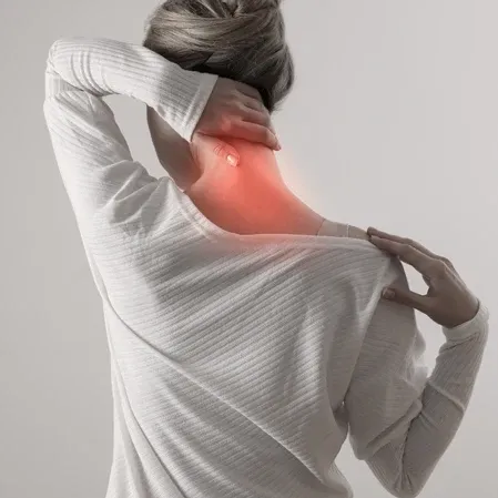 A woman holding her neck with one hand and shoulder with the other, showing signs of neck pain.
