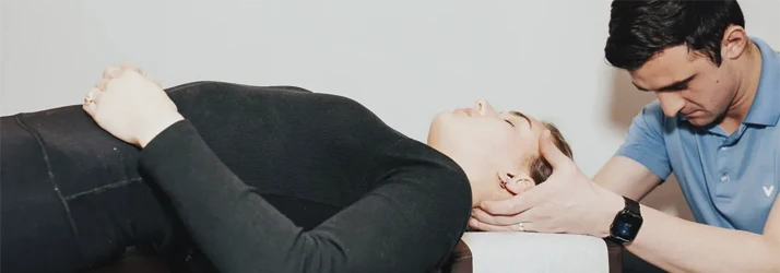 Dr. Zac Pinter performing neck adjustment on female patient lying down.